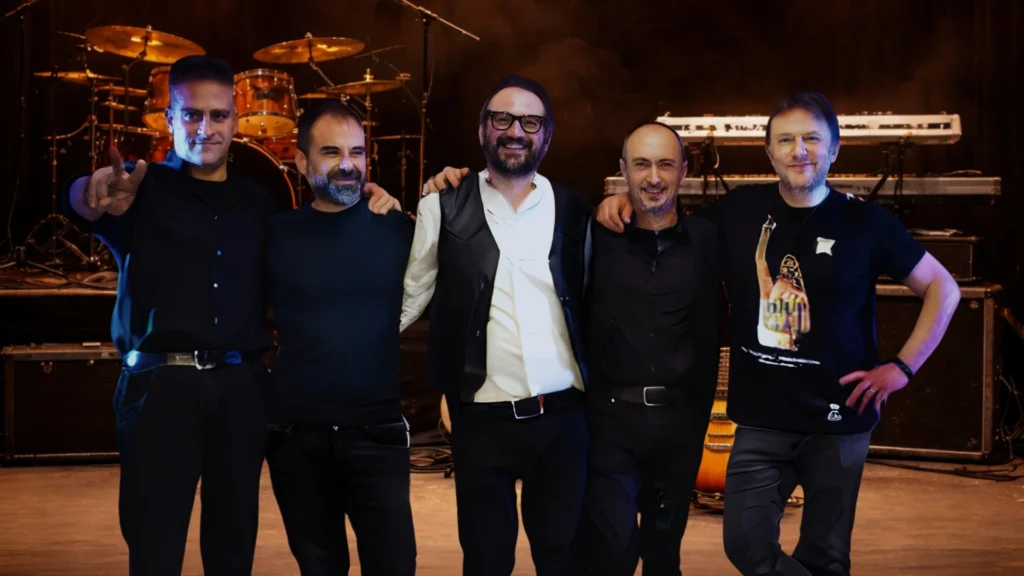 Musicisti della band I Viandanti tributo ai Nomadi in posa sul palco con strumenti musicali.